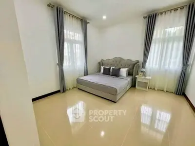 Spacious bedroom with elegant decor and large windows for natural light.