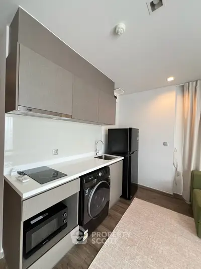 Modern kitchen with sleek appliances and stylish cabinetry in a contemporary apartment.