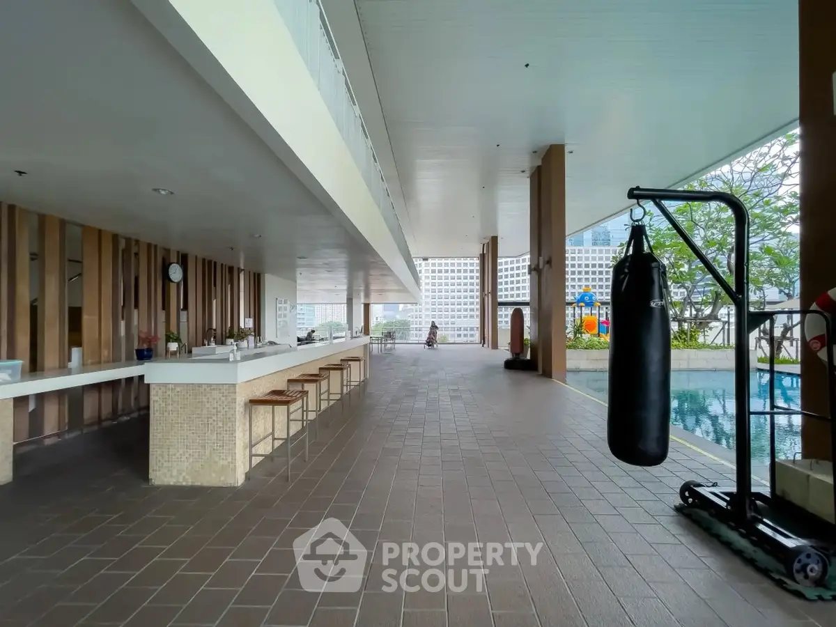 Modern apartment building with poolside gym and open-air seating area.