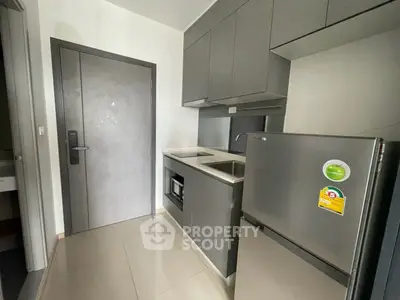 Modern compact kitchen with sleek cabinetry and stainless steel appliances in a stylish apartment.