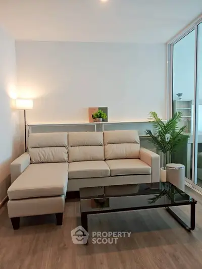 Modern living room with sleek beige sofa and glass coffee table, perfect for stylish urban living.