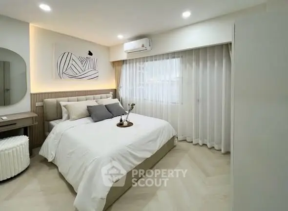 Modern bedroom with elegant decor and natural light, featuring a cozy bed and stylish furnishings.