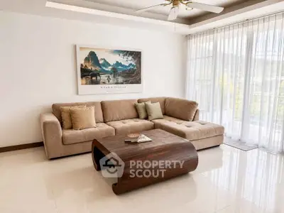 Elegant living room with plush sectional sofa and modern wooden coffee table, featuring large windows with sheer curtains.
