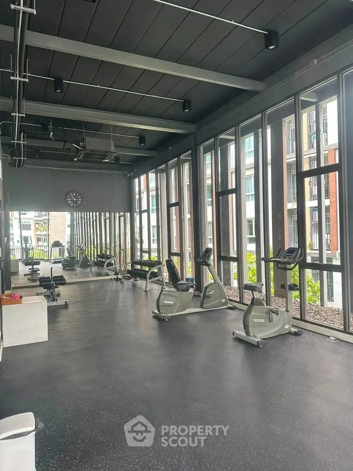Modern gym with large windows and exercise equipment in a luxury apartment building.