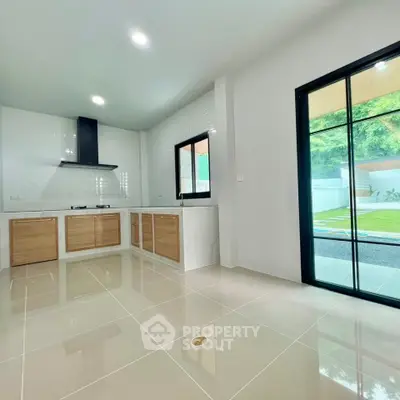 Modern kitchen with sleek design and garden view, featuring open layout and gas stove.