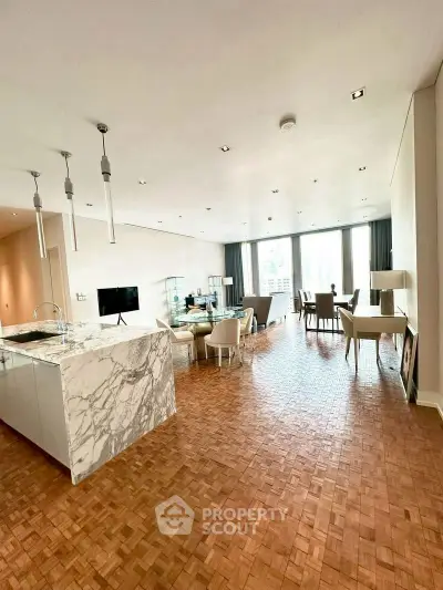 Spacious open-plan living room with elegant marble kitchen island and parquet flooring.