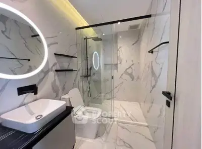 Luxurious modern bathroom with marble walls and sleek glass shower enclosure.