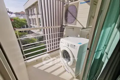 Compact balcony with washing machine and air conditioning unit in modern apartment