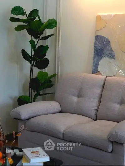 Cozy living room with plush sofa and decorative plant, perfect for relaxation.