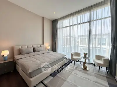 Luxurious bedroom with large windows and elegant decor, featuring a king-sized bed and cozy seating area.