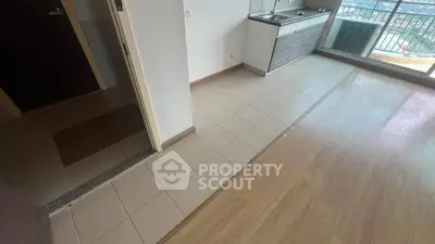 Modern apartment with open kitchen and balcony view, featuring sleek flooring and ample natural light.