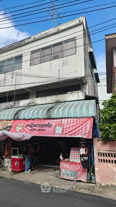 Commercial building with street-level shop and residential upper floors in urban area.