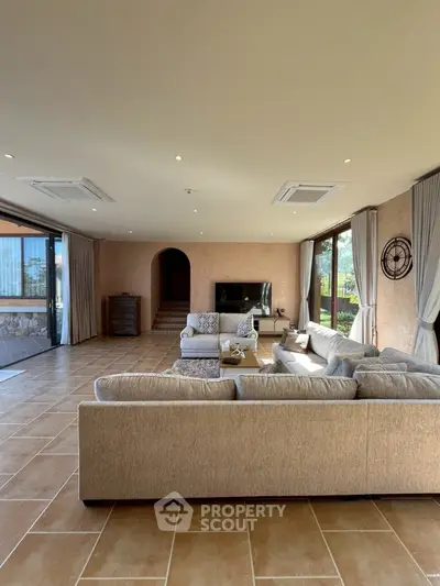 Spacious living room with elegant decor and large windows offering natural light and garden view.