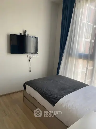 Modern bedroom with wall-mounted TV and large window with blue curtains.