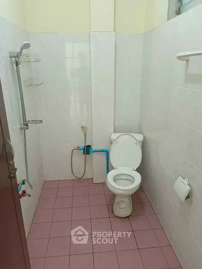 Simple bathroom with shower and toilet, tiled walls and floor.