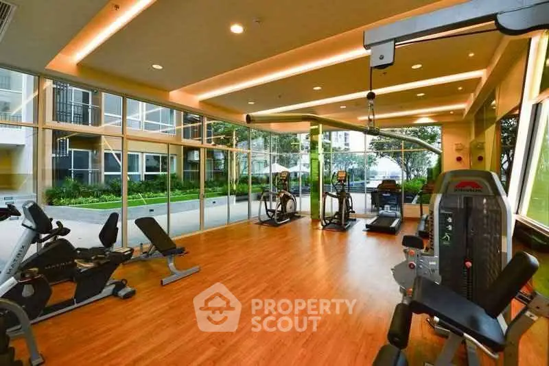 Modern gym with state-of-the-art equipment and large windows overlooking lush greenery.