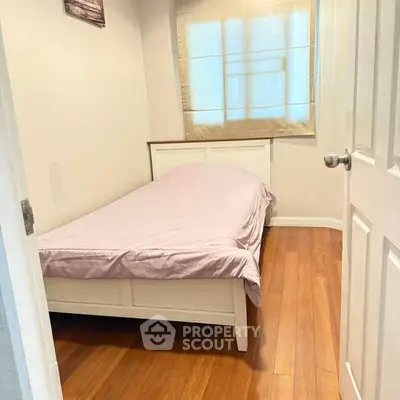 Cozy small bedroom with wooden flooring and natural light
