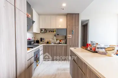 Modern kitchen with sleek cabinetry and open layout, featuring built-in oven and ample counter space.