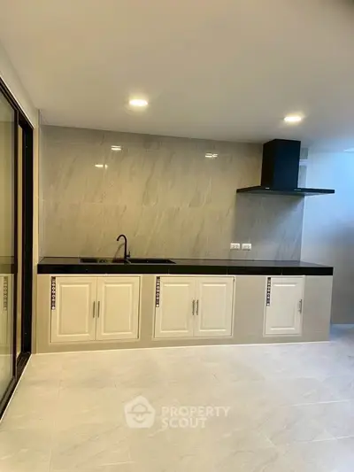 Modern kitchen with sleek cabinetry and black countertop in a stylish apartment.
