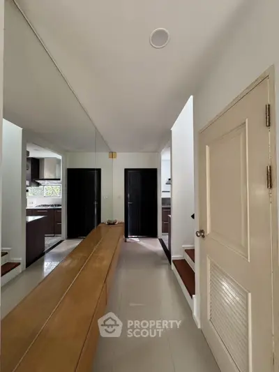 Modern kitchen with sleek cabinetry and open layout, featuring a long wooden counter and stylish design.