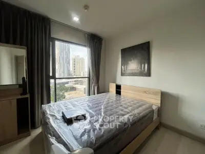 Modern bedroom with large window and city view, featuring stylish decor and natural light.