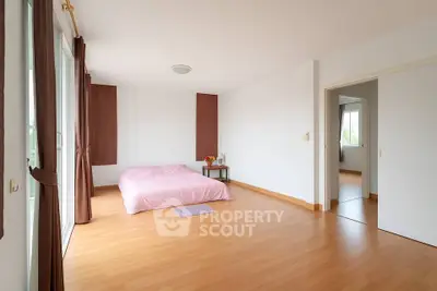 Spacious minimalist bedroom with wooden flooring and natural light