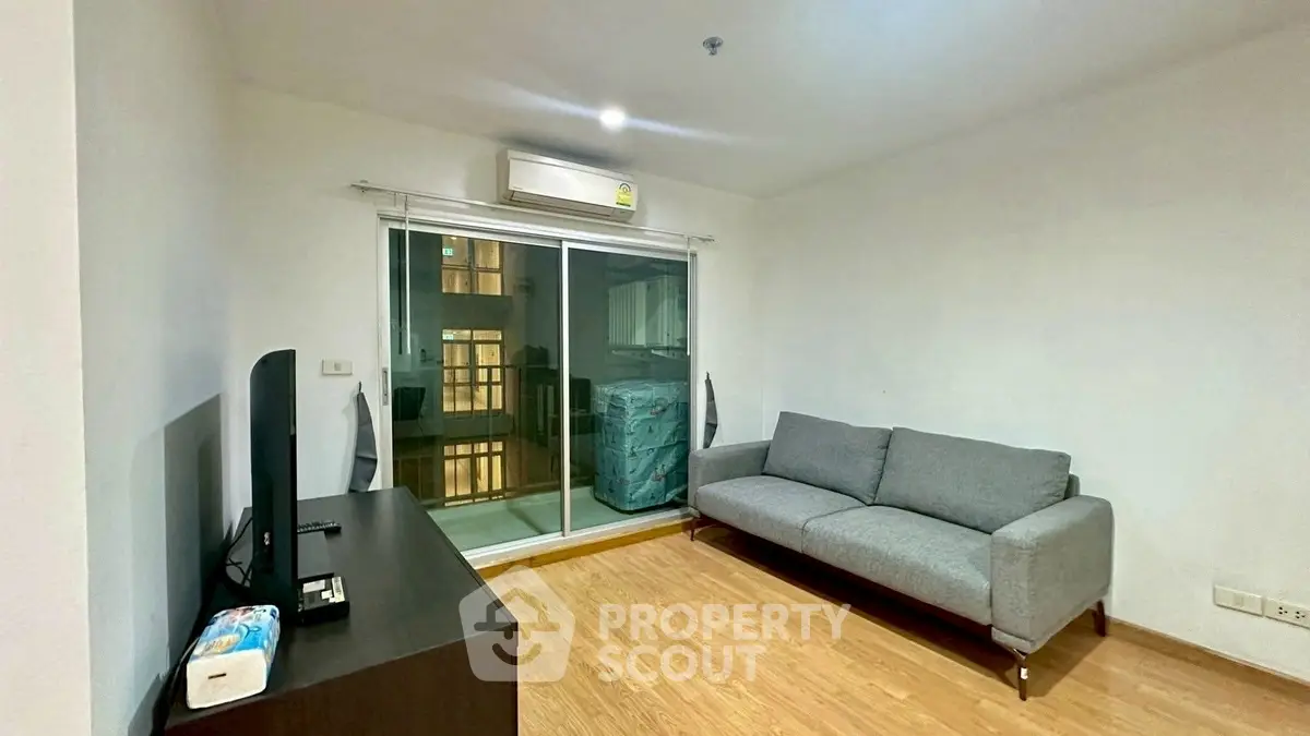 Modern living room with sleek sofa and TV, featuring a balcony view.