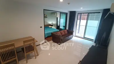 Modern apartment interior with open living room and bedroom view, featuring sleek furniture and natural light.