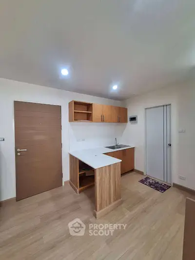 Modern kitchen with wooden cabinets and sleek countertops in a cozy apartment.