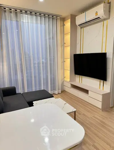 Modern living room with sleek furniture and large TV, featuring elegant curtains and air conditioning.