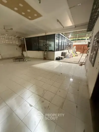 Spacious industrial-style interior with tiled flooring and large windows, ideal for creative workspace or storage.