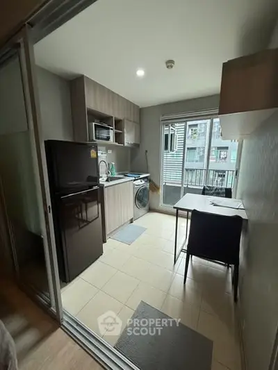 Modern kitchen with appliances and dining area in a compact apartment setting.