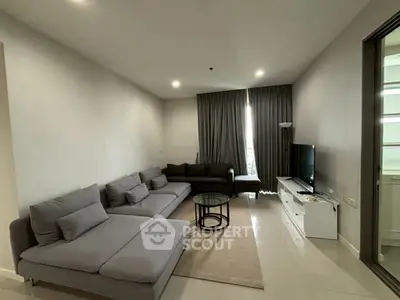 Spacious modern living room with sleek gray sofas and a flat-screen TV, perfect for relaxation.