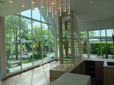 Spacious modern living room with large windows and lush garden view, featuring elegant lighting and open layout.