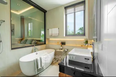 Luxurious bathroom with freestanding bathtub and large window offering serene views.