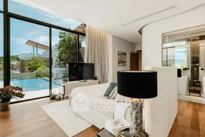 Luxurious living room with pool view, elegant decor, and floor-to-ceiling windows in modern home.