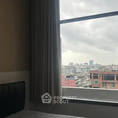 Cozy bedroom with city view through large window and elegant curtains.