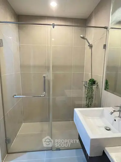 Modern bathroom with glass shower enclosure and sleek sink design.