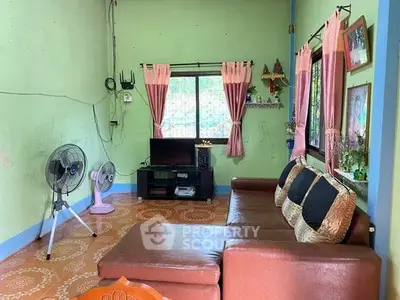 Cozy living room with green walls, brown sofa, and window view