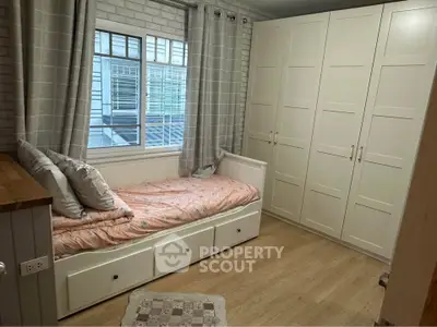 Cozy bedroom with built-in wardrobe and daybed, perfect for small spaces.