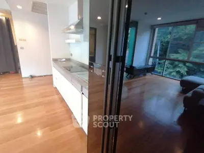 Spacious modern apartment with open kitchen and large windows overlooking greenery.