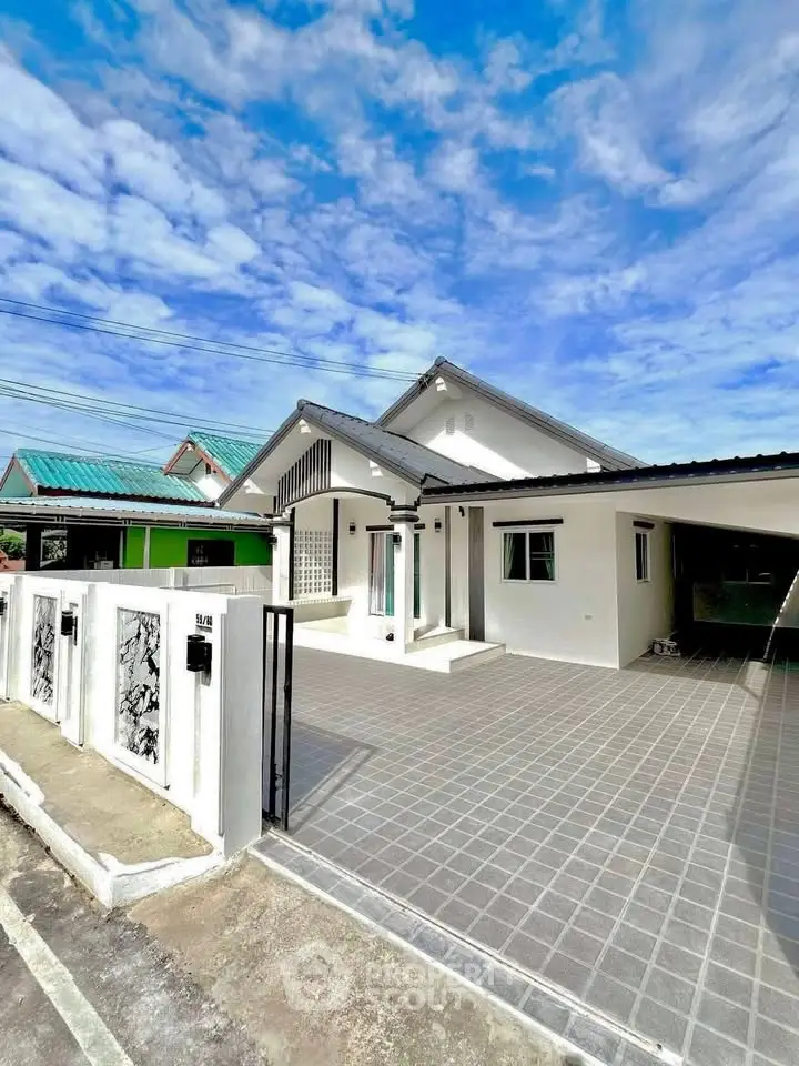Charming single-story home with spacious driveway and modern exterior design under a clear blue sky.