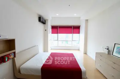 Spacious bedroom with modern decor and large window offering city views