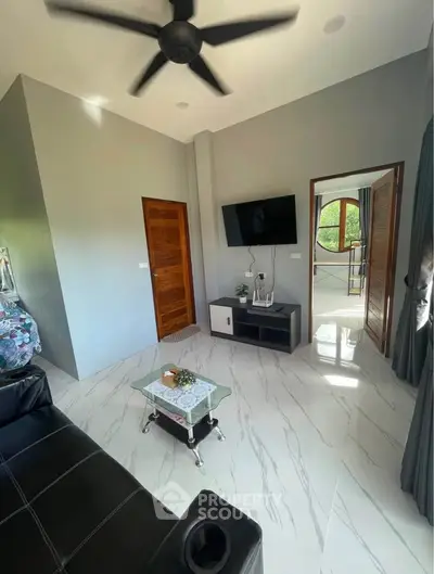 Modern living room with sleek design, featuring a wall-mounted TV, stylish furniture, and large windows for natural light.