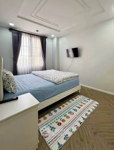 Cozy bedroom with modern decor, featuring a wall-mounted TV and large window for natural light.