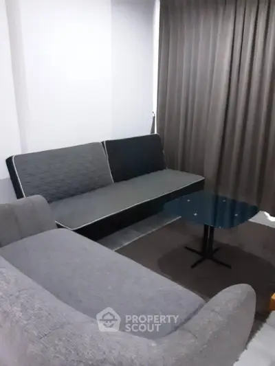 Cozy living room with modern gray sofa and glass coffee table, perfect for relaxation.