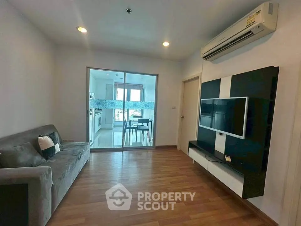 Modern living room with sleek TV setup and view into stylish kitchen