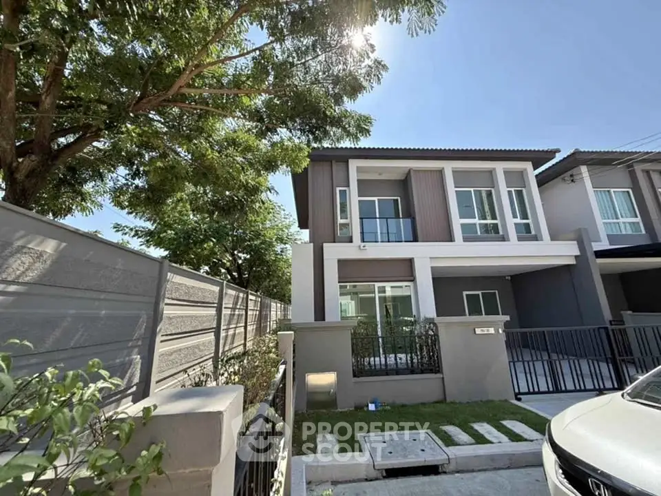 Modern two-story house with a sleek design and spacious driveway under a clear blue sky.