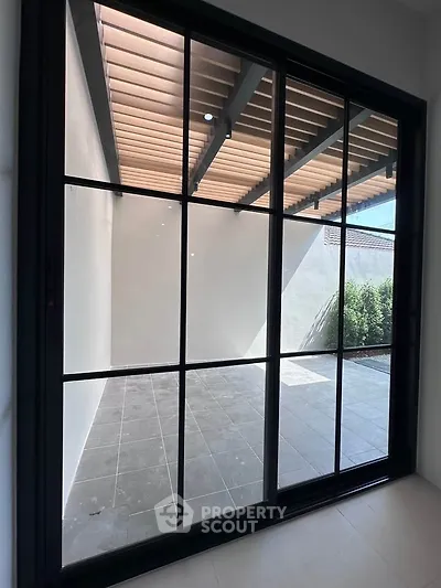 Modern patio with large sliding glass doors and tiled flooring, perfect for outdoor relaxation.