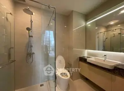 Modern bathroom with glass shower and sleek vanity in luxury apartment.
